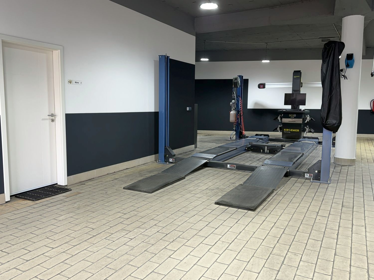 Zweite Ansicht der Halle mit Hebebühne, Achsmessgerät und Bürotür